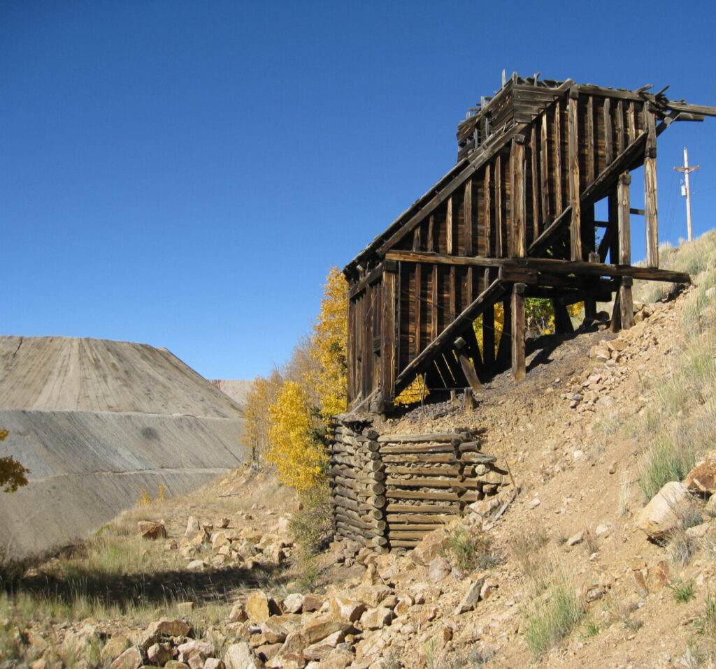 A historic mining headframe wooden scaffolding, in an arid mountainous landscape.