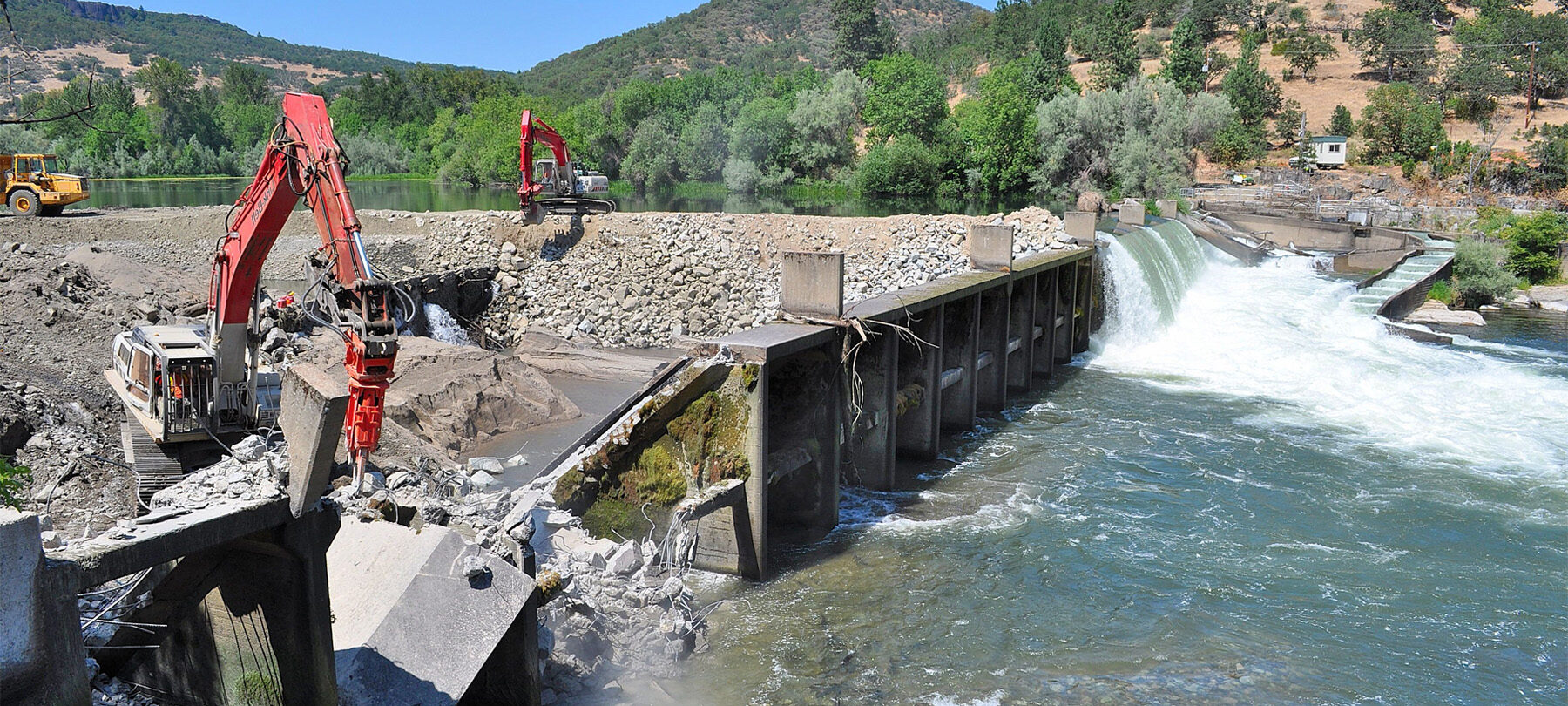 Construction vehicles deconstructing a dam.