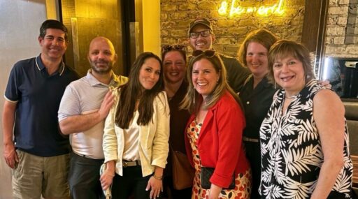 Indoor snapshot of a group of 8 people in business casual attire.