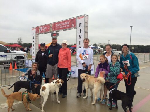 Group photo of people and their dogs posing at the finish line of a Walk and Fun Run