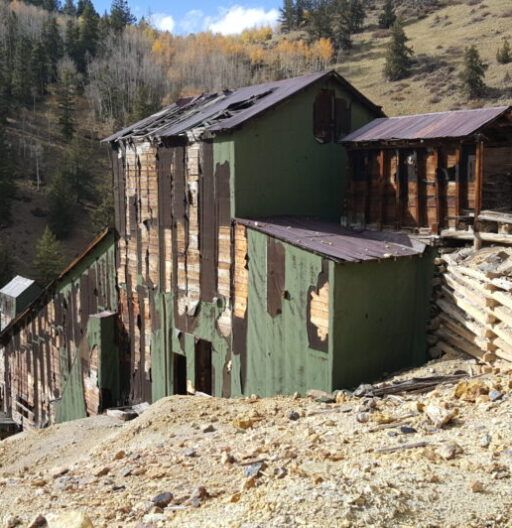 A decrepit abandoned mine structure in a hilly area.