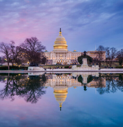 The U.S. Capitol building and its reflection in water during a colorful sunset.
