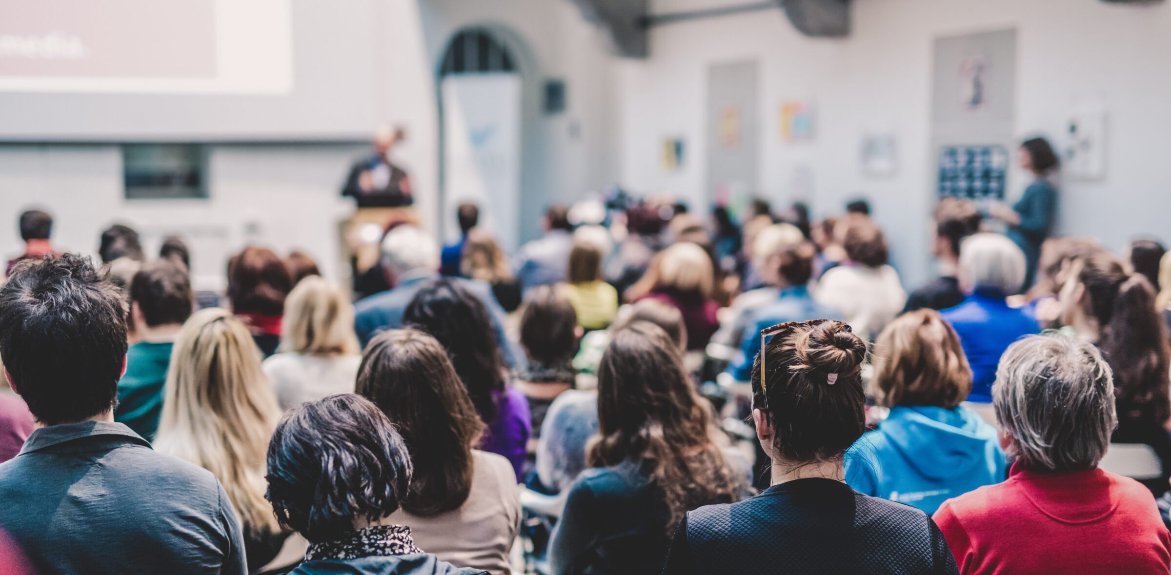 Rear view of an audience in a lecture hall, attending a lecture.