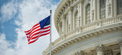 Washington DC Capitol dome detail with the American flag waving in the wind.