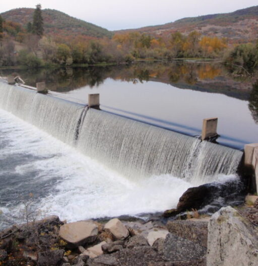 View of water from a retaining pond flowing over the retaining wall at the dam.