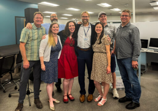 Office group photo of 8 people in business casual attire.