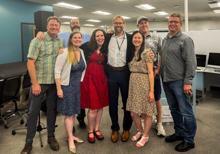 Office group photo of 8 people in business casual attire.