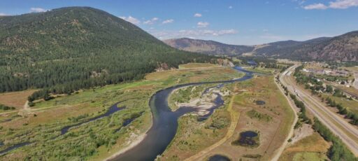 Arial landscape view of a river, road, and mountains.