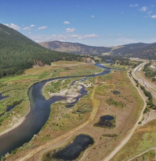 drone footage of a swath of land with a winding river flanked by hills.