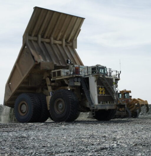 A heavy-duty dump truck with its dump bed raised for unloading.
