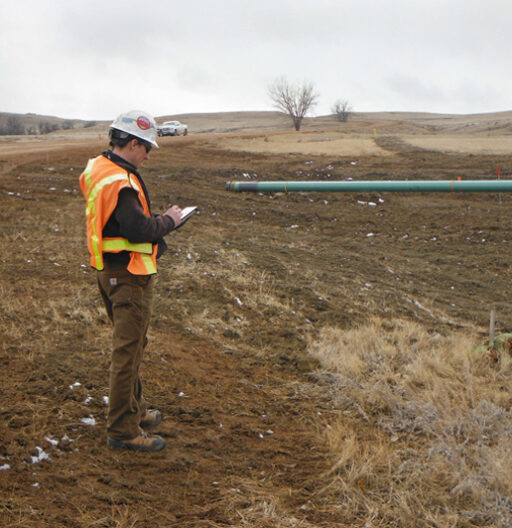 A man in a safety vest doing inspection on a new pipeline.