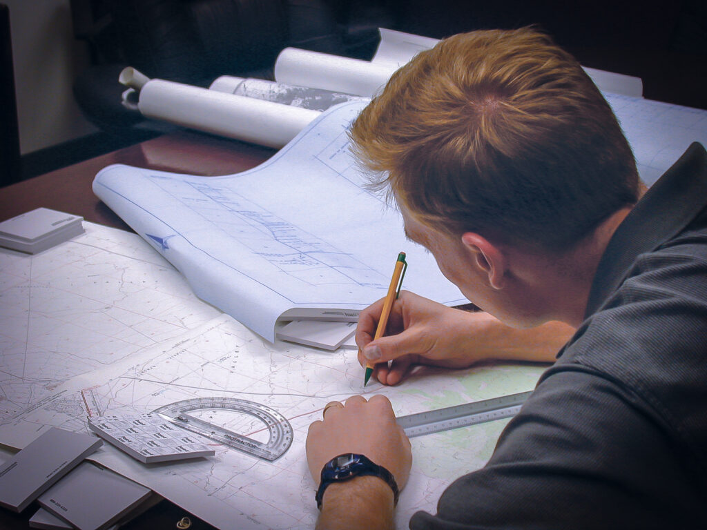 Over the shoulder view of a person making marks on a map of terrain.