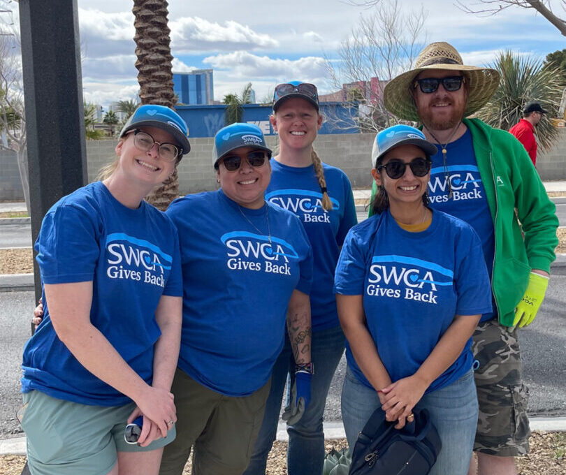 Five people pose for group photo outdoors, wearing SWCA Gives Back tee shirts