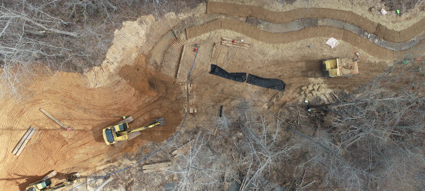 Aerial view of early stages of a land development project. Construction vehicles clear and level the land.