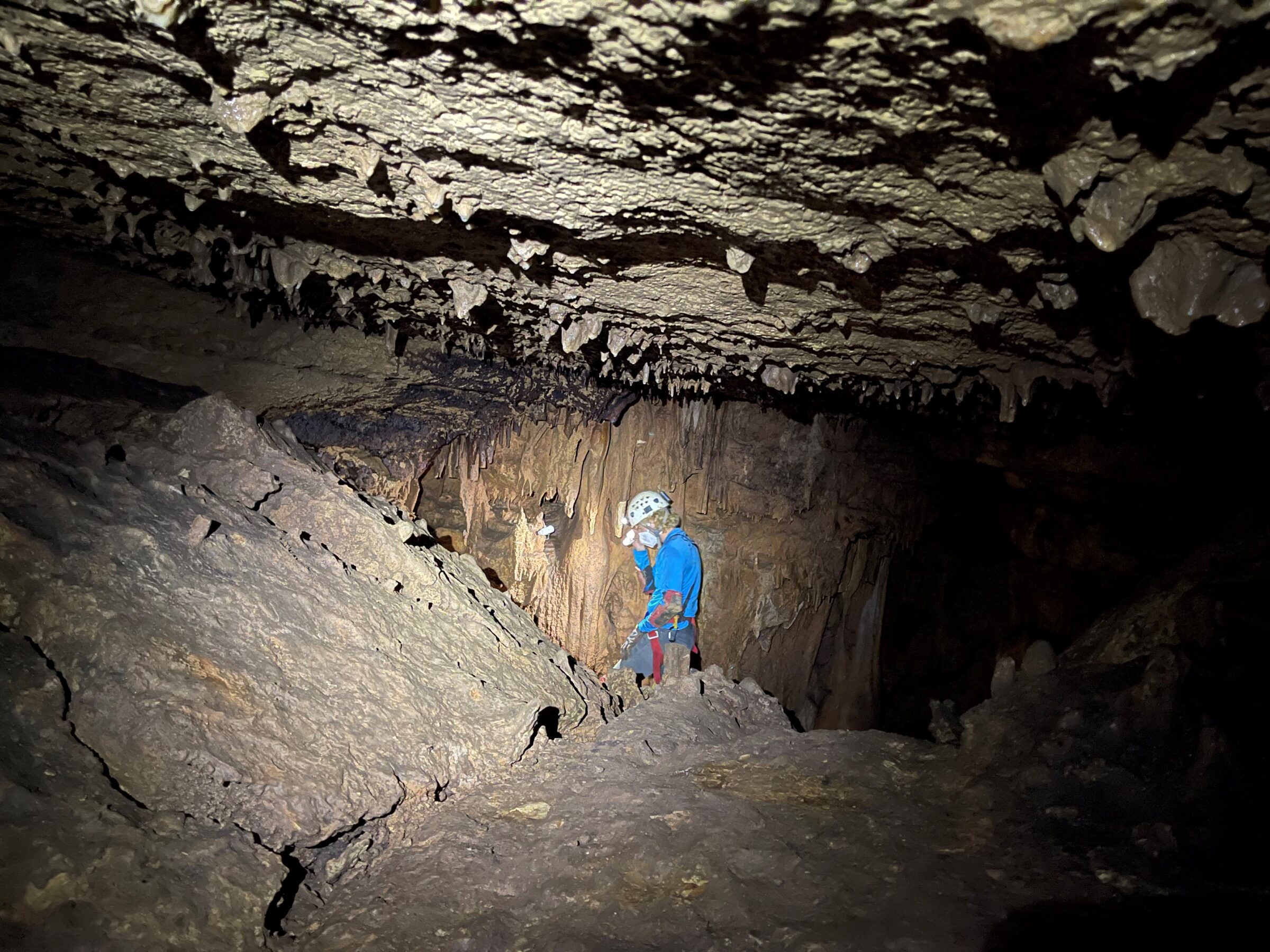 a person is at the far end of a cave lit by spotlights.