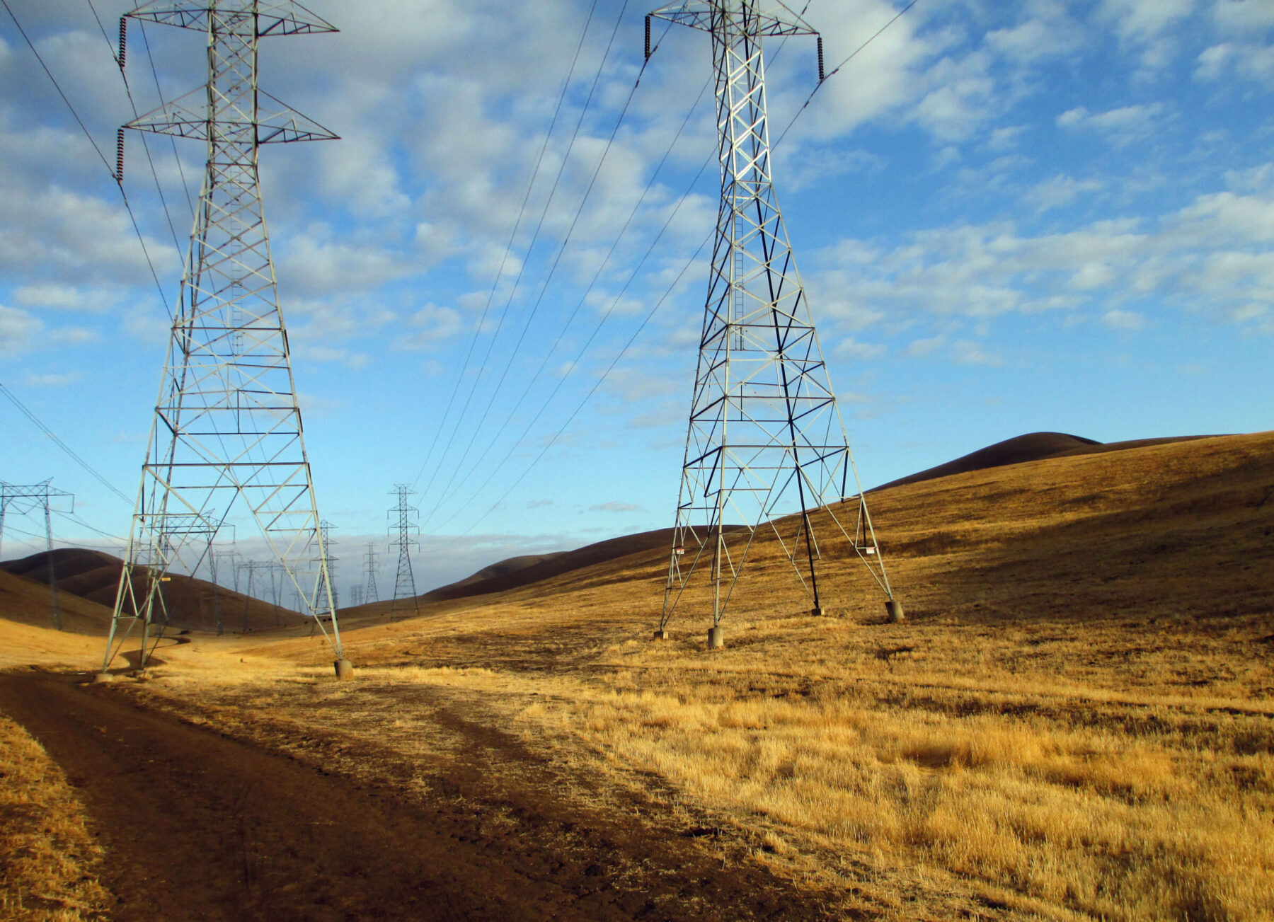 Rolling hills, transmission towers on brown vegetation.