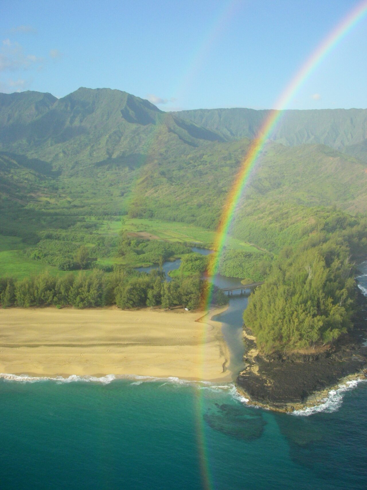 Drone photo over the ocean looking inland at a Double rainbow.