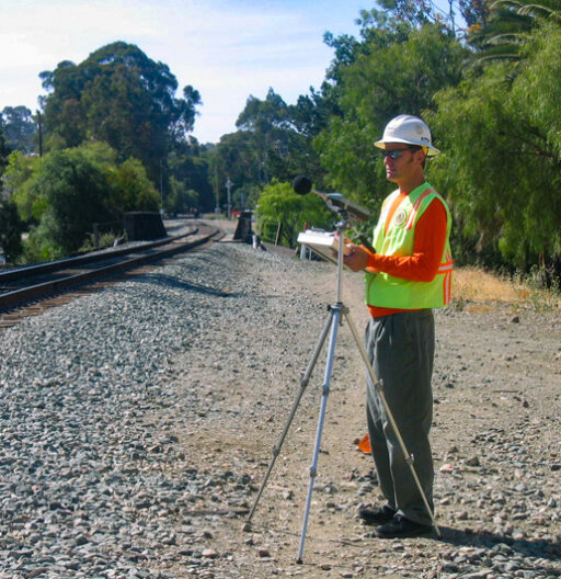 SWCA employee with a survey tripod set up near railroad tracks.