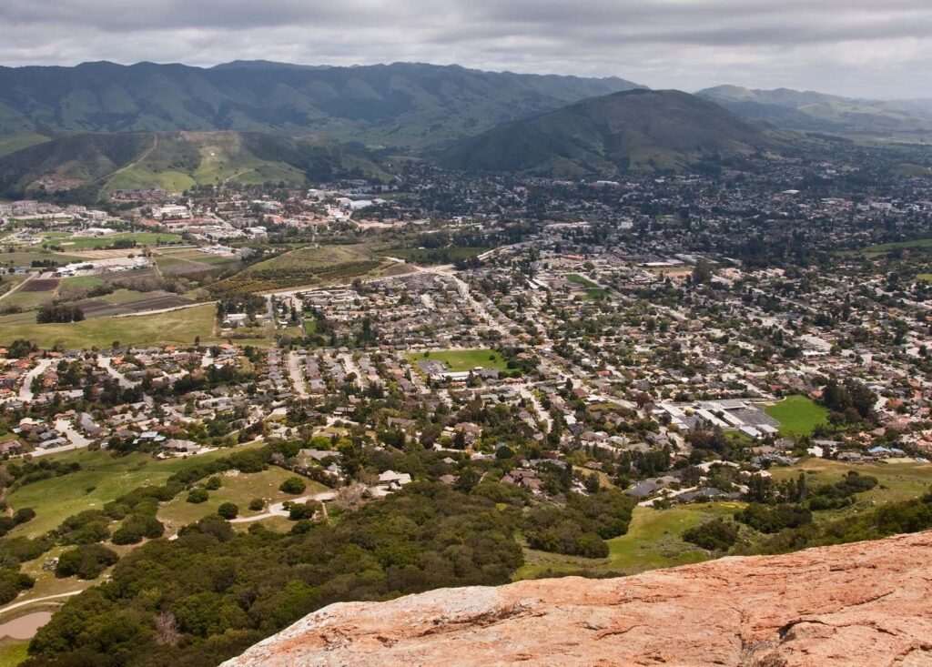 Aerial photo of a town in the foothills of a mountain range.