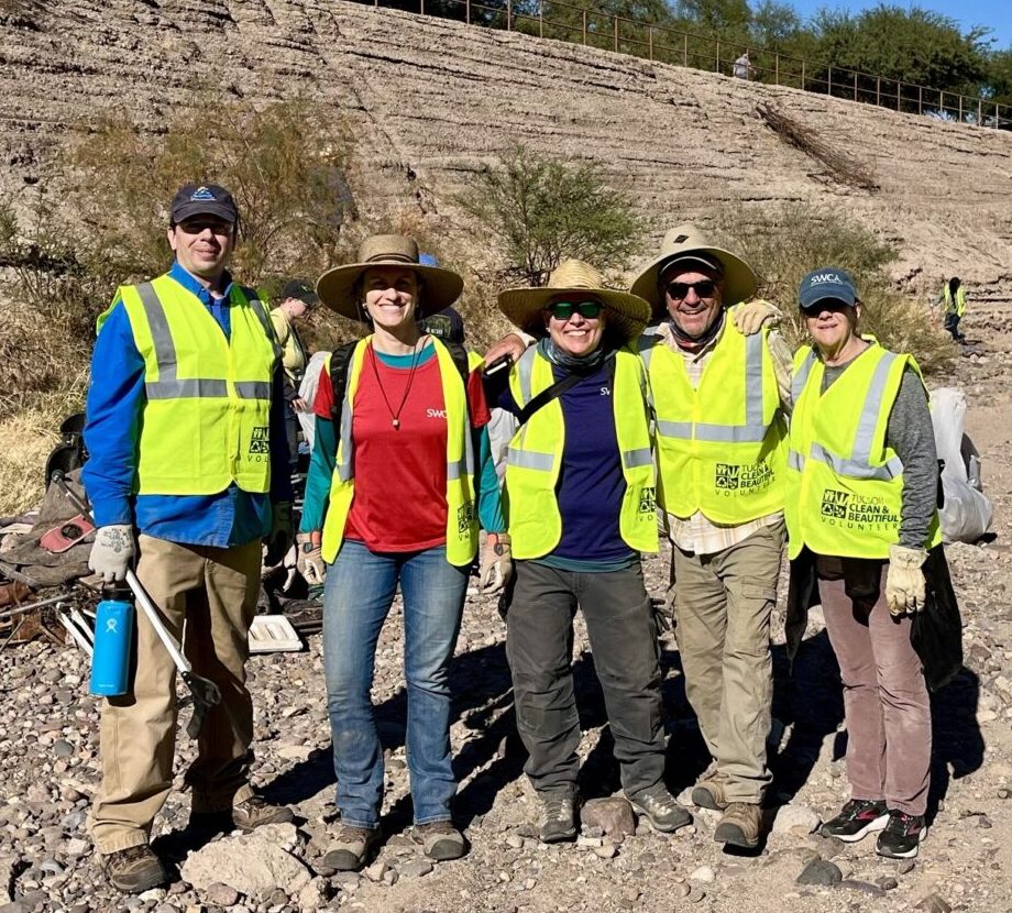 Five employees in sun hats and safety vests outdoors on a bright day.